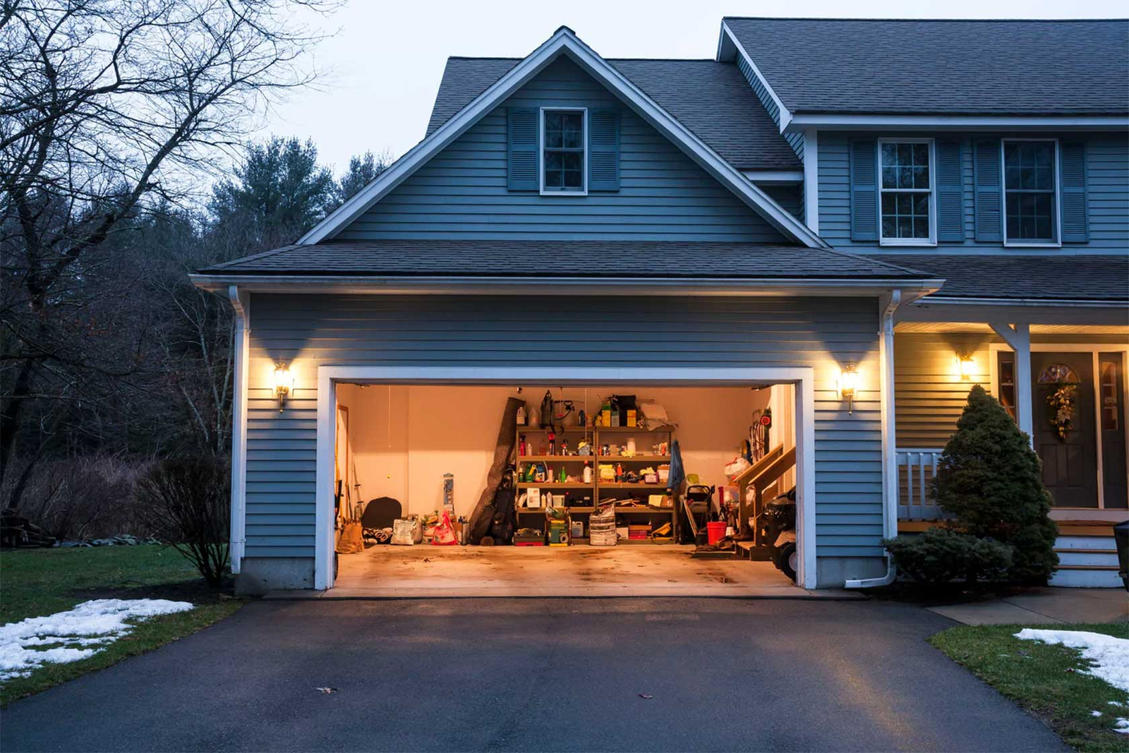 The image depicts a homeowner conducting maintenance on a garage door amidst snowy weather. This visual emphasizes the importance of regular upkeep during extreme conditions to prevent issues such as freezing or mechanical failures. Proper maintenance includes lubricating moving parts, checking weather seals, and ensuring the door operates smoothly despite harsh weather.